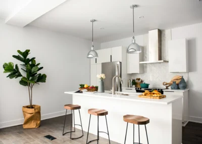 Modern handleless white kitchen with central island and pendant lights, illustrating contemporary open plan kitchen design in Manchester and Cheshire
