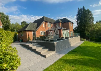 Tiered terrace, composite decking and porcelain patio with glass balustrade forming a landscaped Cheshire garden