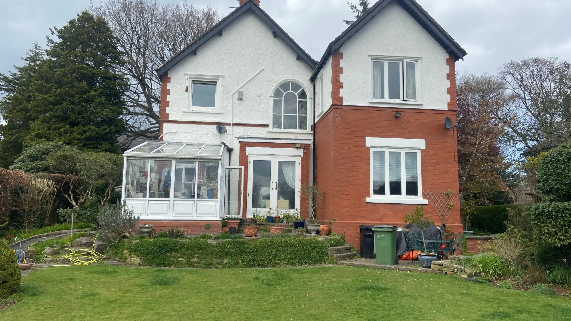 Rear view of red brick and white rendered detached house before extension and landscaping in Cheshire