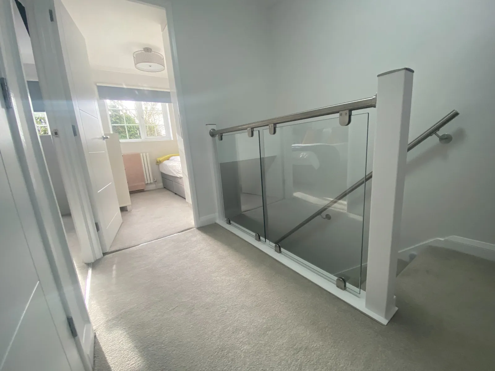 Modern glass balustrade staircase with white newel posts in Stockport property