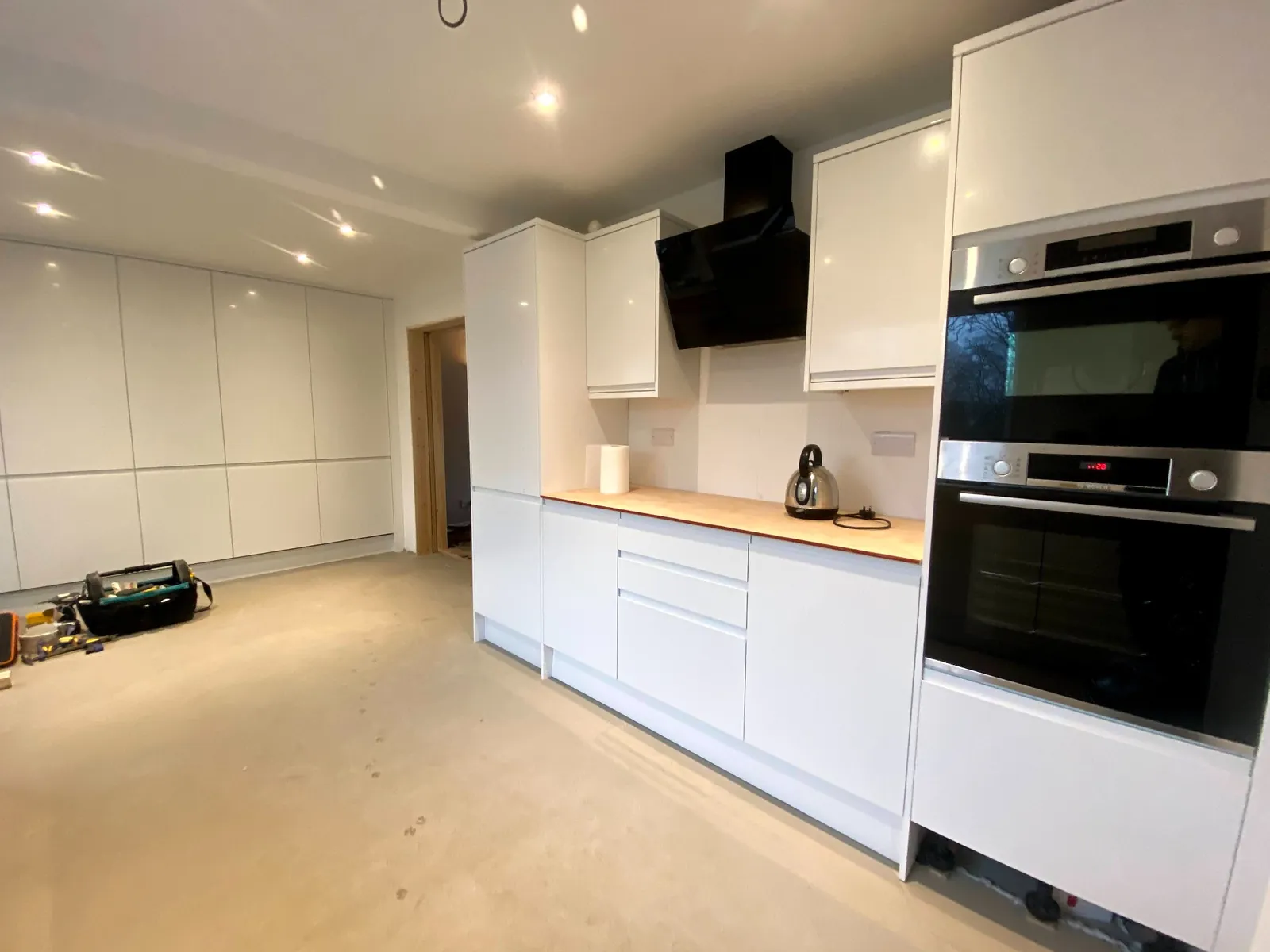 Modern white handleless kitchen refurbishment in Stockport with full height storage wall